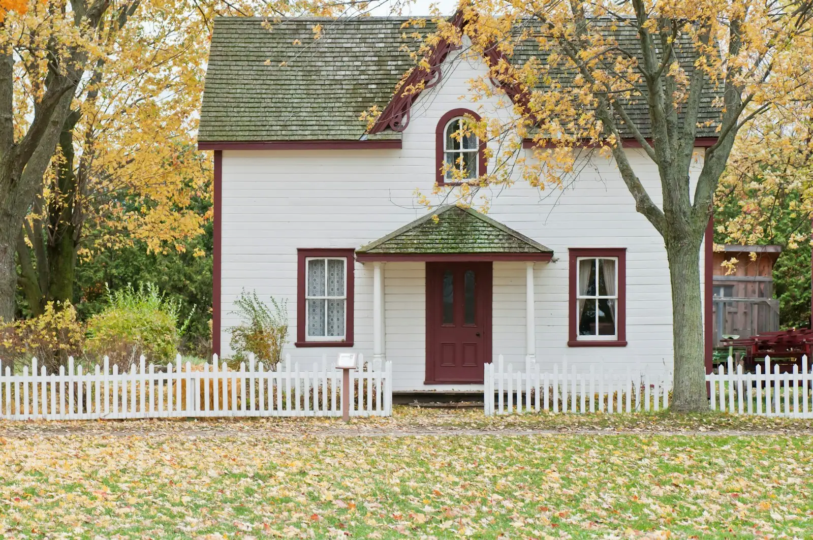 White cottage with a picket fence in autumn