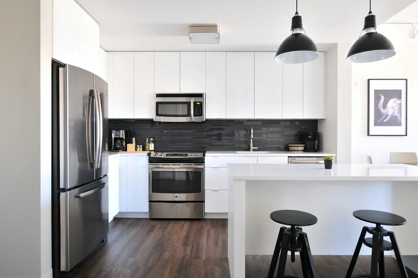 Bright white kitchen with black pendants and a breakfast bar
