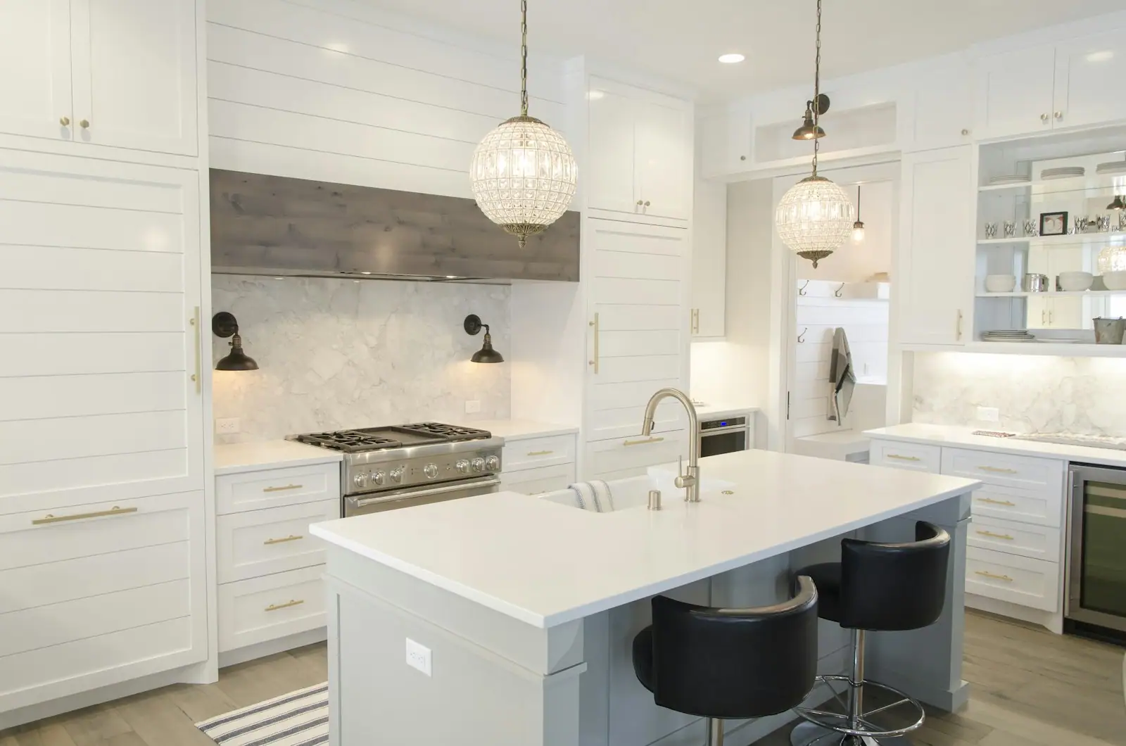 White kitchen with a marble-look island and lantern pendants