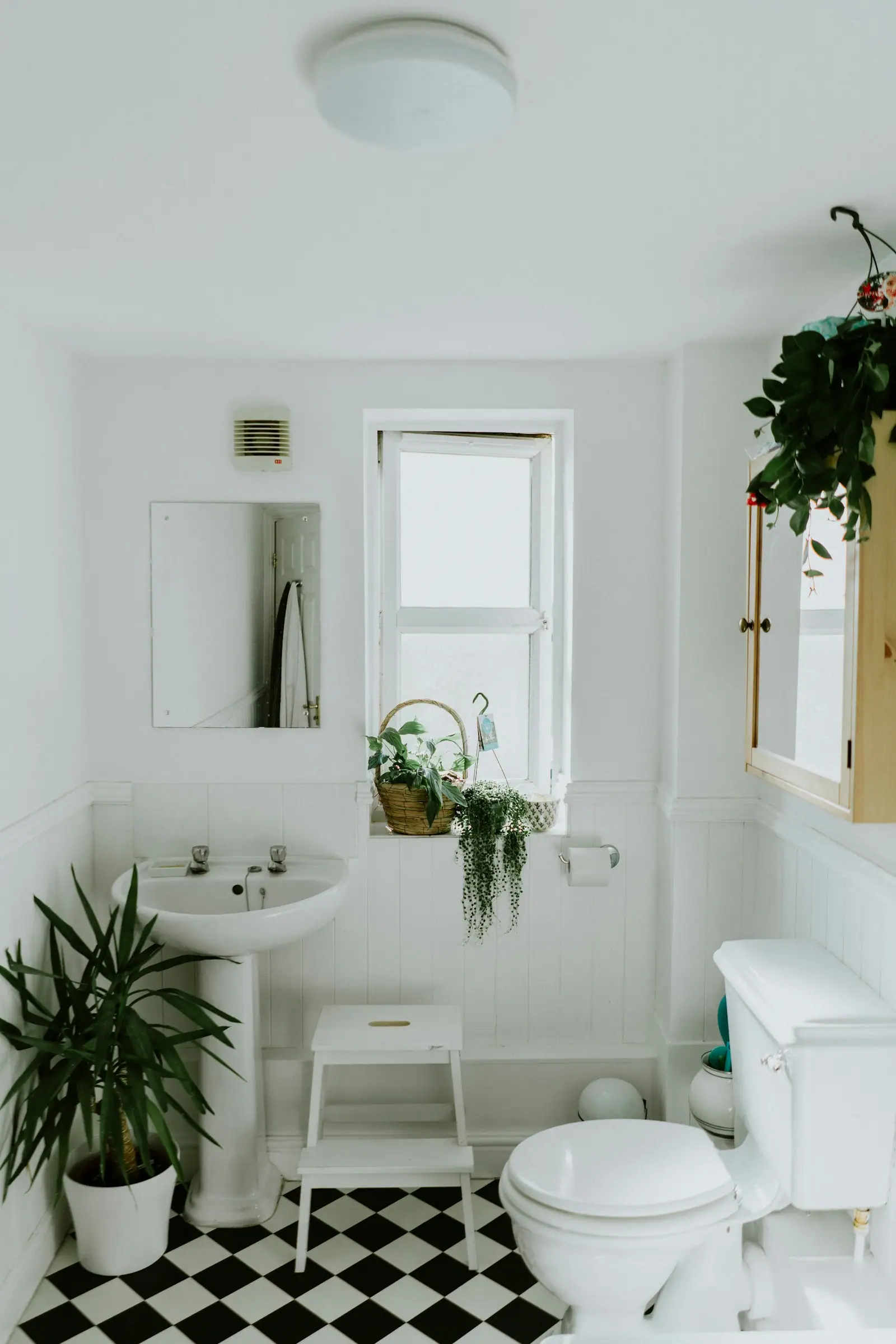 Compact bathroom with pedestal sink and checkerboard floor