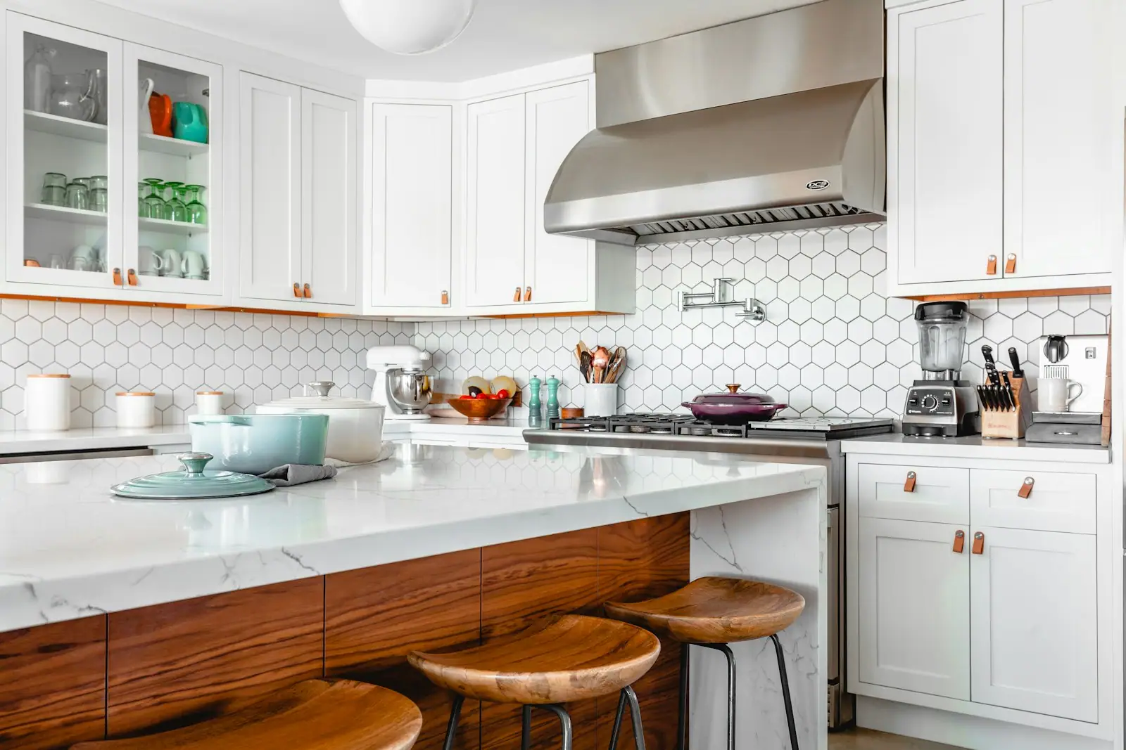 White kitchen with a wood-wrapped island and stainless hood