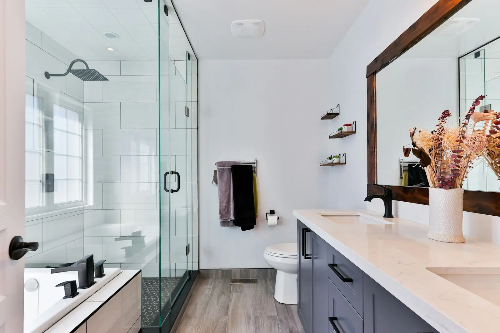 Bathroom with a glass shower, navy vanity and large mirror