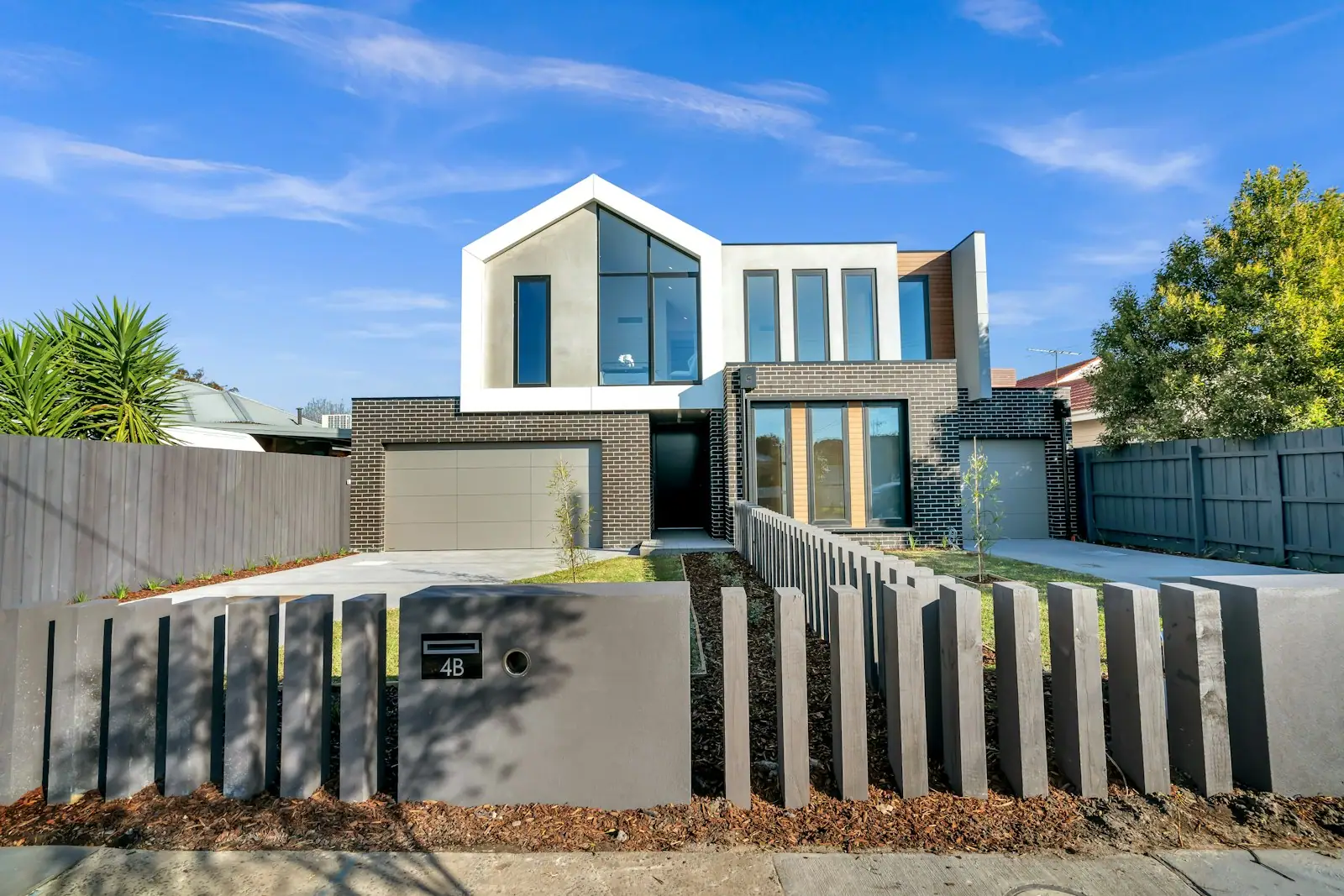 Modern gabled home behind a dark slatted fence