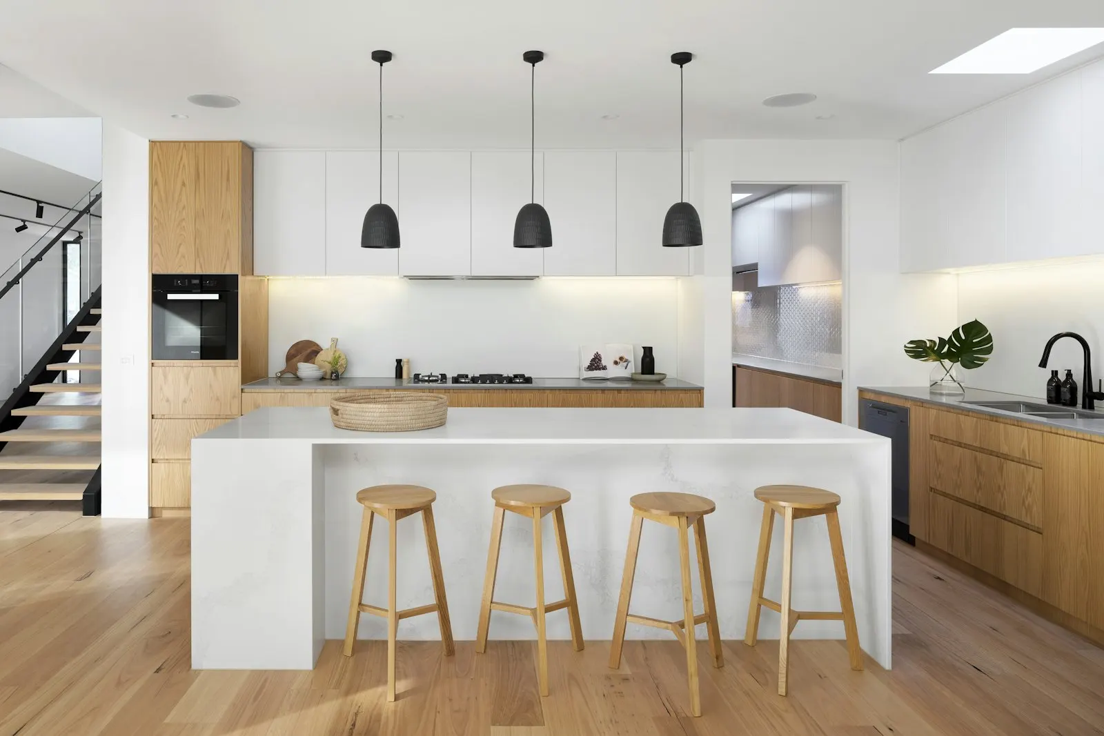 White and oak kitchen with a waterfall island and wood stools