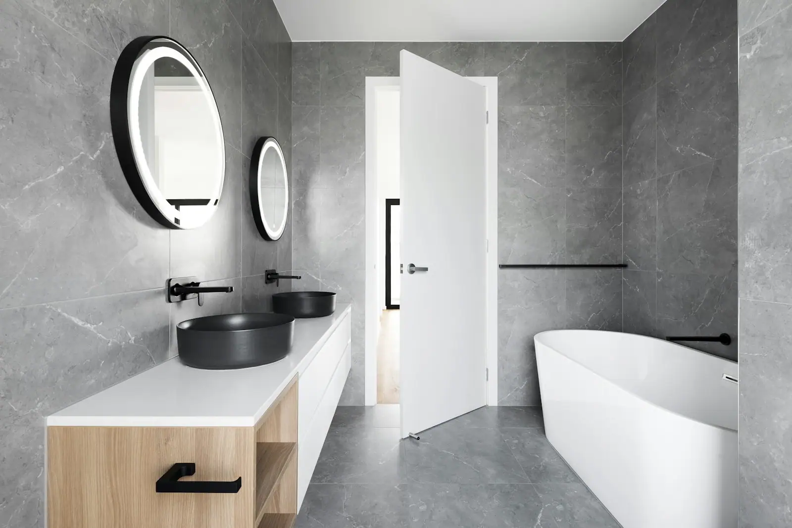 Primary bath with round mirrors, floating vanity and freestanding tub